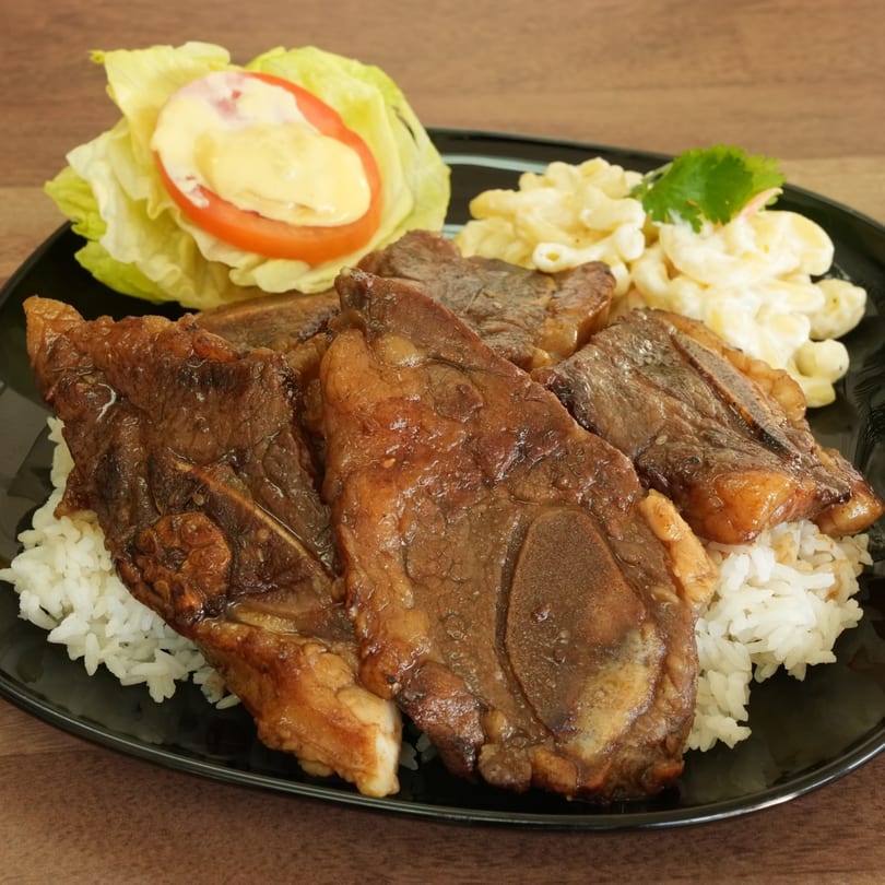 Thai BBQ short ribs with rice, macaroni salad, and a side salad with dressing.